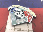 Metallic badge with horse design and text on a red and blue background