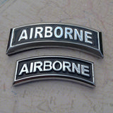 Two 'AIRBORNE' military badges on a textured surface