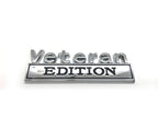 A chrome plated, black enamel zinc alloy emblem with the text 'Veteran EDITION' on a white background.